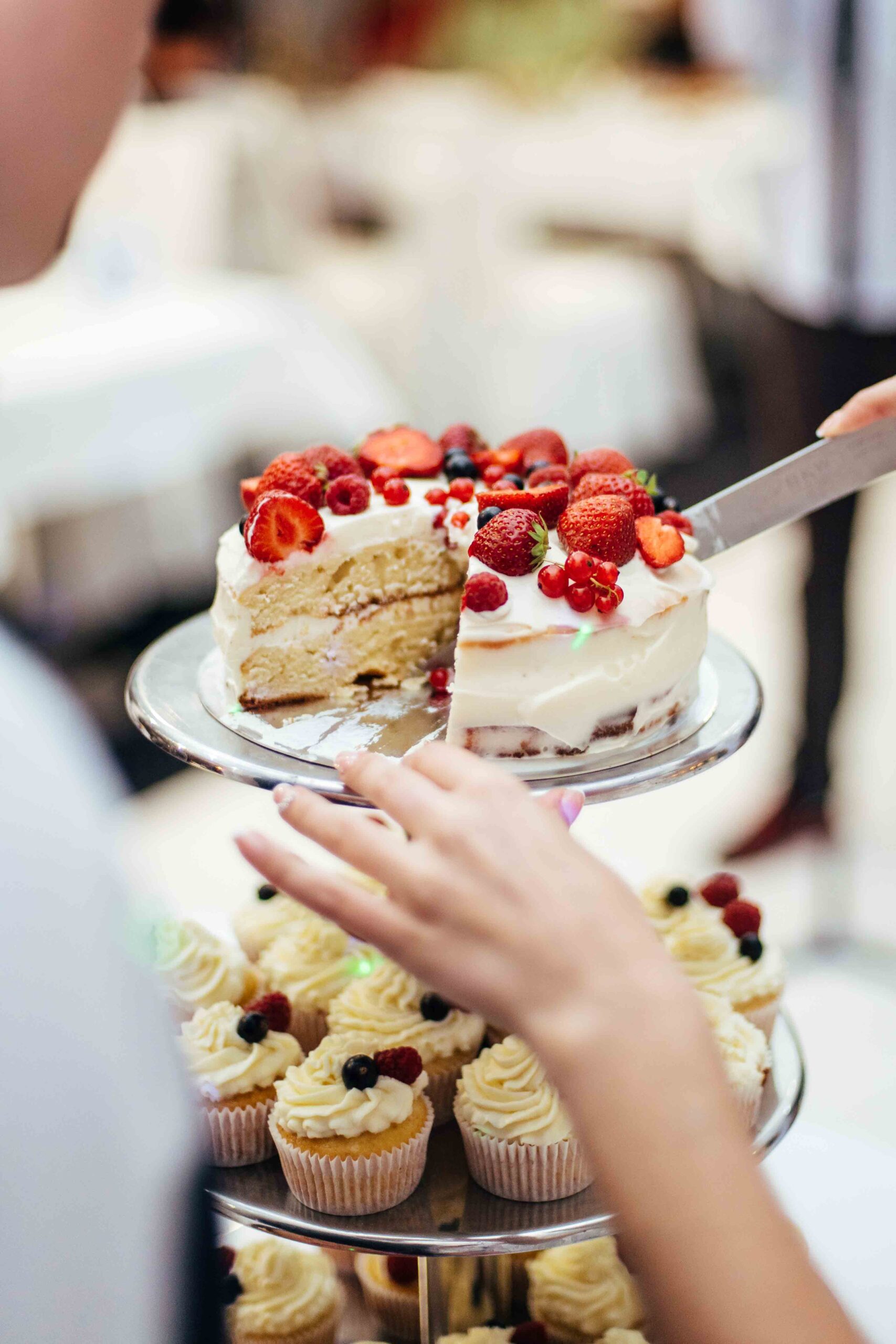 Et kagefad i tre etager med cupcakes i bunden og en tærte med jordbær på toppen.