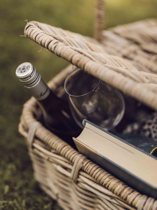En kurv med en bog, en hvidvin og et hvidvinsglas.