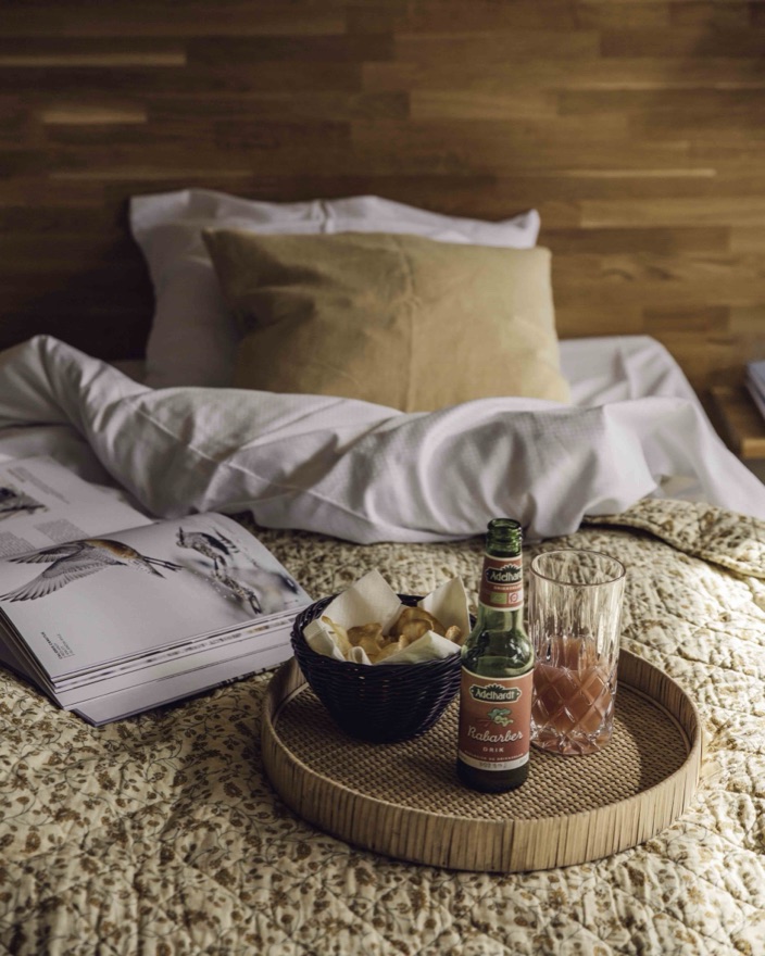 Bakke med snacks og et glas på sengen i et hotelværelse